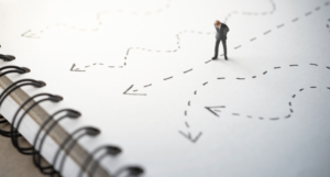 Man looking at directional arrows on notebook paper